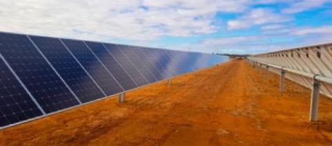solar panels lined up in a solar panel farm on red dirt